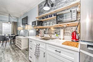 Enjoy cooking in this well-equipped kitchen with a refrigerator, toaster, and microwave, and ample workspace on a wooden countertop.