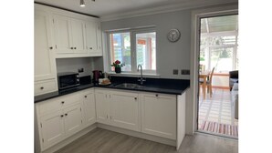 Cucina con mobili bianchi, piano di lavoro nero, lavello e finestra con vista all'esterno.
