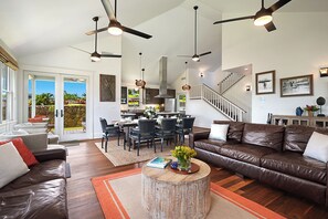 Enjoy a spacious open-plan living space with a dining area, kitchen, and seating area, featuring a staircase and large windows with views of the surrounding landscape.