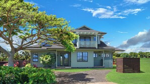 A two-story house with a front porch, a covered patio, and a well-maintained lawn. - Plantation House by Destination Kauai - Poipu Beach Estates, Central A/C, 3BD (Koloa)
