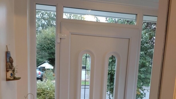 A white door with a small window, a wooden bench, and a wall-mounted light fixture.