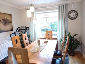 Un comedor con una mesa de madera, sillas, un reloj y una planta en maceta.