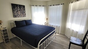 A bedroom with a bed, a chair, a nightstand, and a painting on the wall. - Private Beach Home (Navarre)