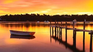 Un lago tranquilo al atardecer, con un muelle y un bote.