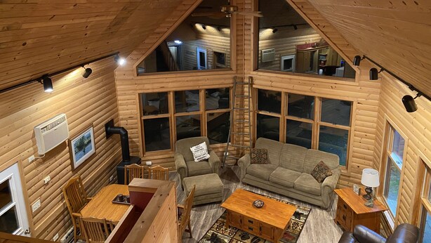 A cozy cabin interior with a dining area, a sofa, and a fireplace. - Cabin in Beautiful Timber Coulee (Westby)