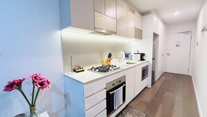 Una cocina moderna con armarios blancos, una estufa a gas y un microondas. Hay un jarrón con flores en la encimera.