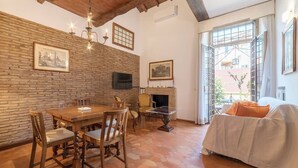 A cozy room with a wooden dining table, chairs, a fireplace, a sofa, and a large window. - Quiet roof terraces close to trevi fountain (Roma)