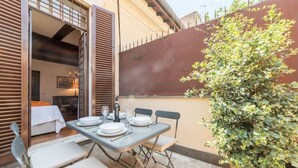 An outdoor dining area with a table set for four, chairs, and a potted plant. - Quiet roof terraces close to trevi fountain (Roma)
