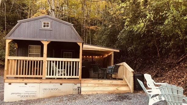 Une cabane dotée d’une terrasse en bois, de meubles d’extérieur et d’un sol en gravier.