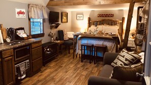 Une chambre à coucher chaleureuse et rustique, dotée d’un lit en mezzanine, de meubles en bois et d’un coin cuisine avec un four encastré.