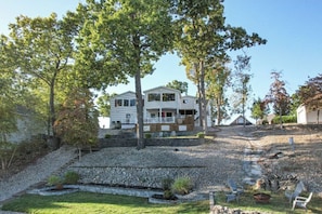 A two-story house with a covered porch, surrounded by trees and a landscaped garden.