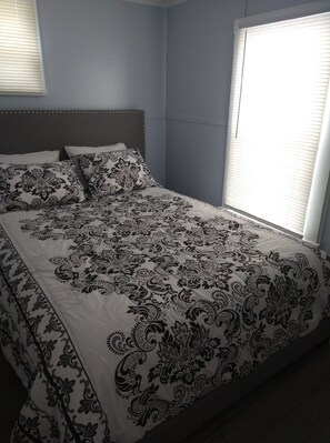 A bedroom with a bed, a headboard, and a window with blinds. - 3 Little Cottages - #2 Sunburst Cottage (Geneva)