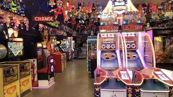 Experience the excitement of classic arcade games in this lively space, featuring a variety of machines, including a Win game with a prize display and a Monopoly game.