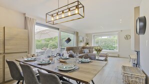 Un espace repas moderne avec une table en bois dressée pour quatre personnes, entourée de chaises grises.