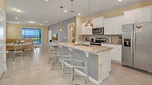 Una cocina moderna con una isla central, electrodomésticos de acero inoxidable e iluminación colgante.