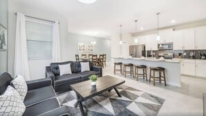 Una sala moderna con sofá, mesa de centro y comedor con taburetes de bar.