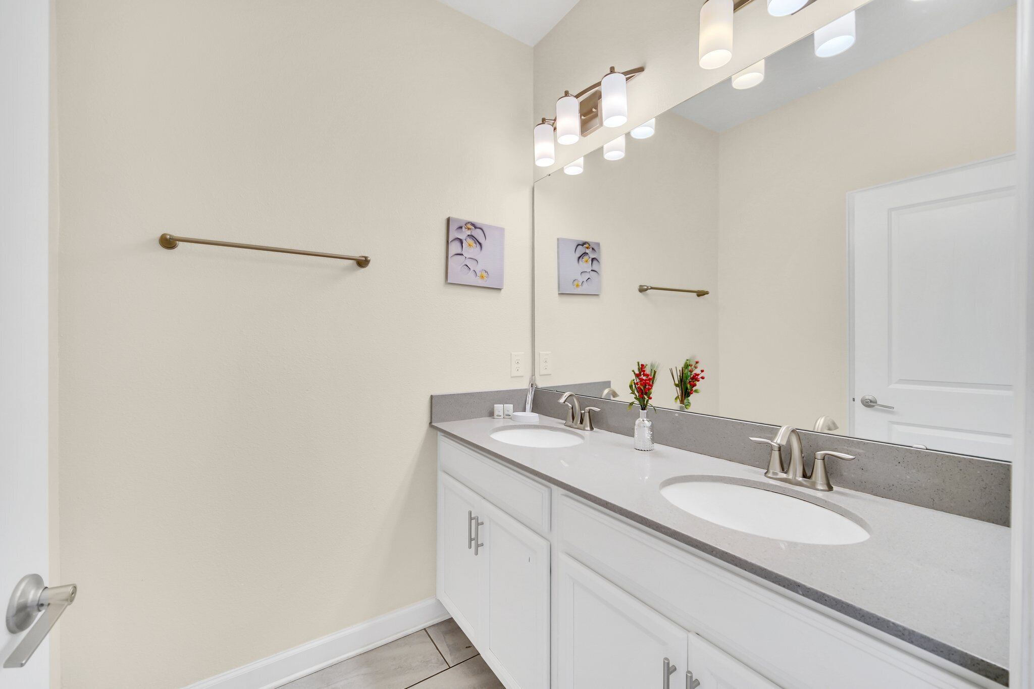 A modern bathroom with two sinks, a large mirror, and wall-mounted towel racks.