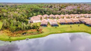 A residential area with multiple houses, a swimming pool, and a lake.