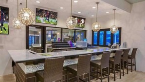 A modern kitchen with a central island, bar seating, and pendant lighting.