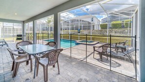 Une terrasse extérieure avec des tables et des chaises, une piscine et une vue sur une serre.