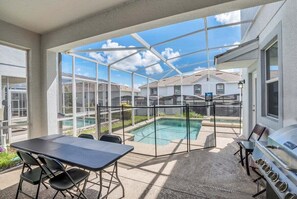 Un patio couvert avec une piscine, des sièges d’extérieur et un barbecue.