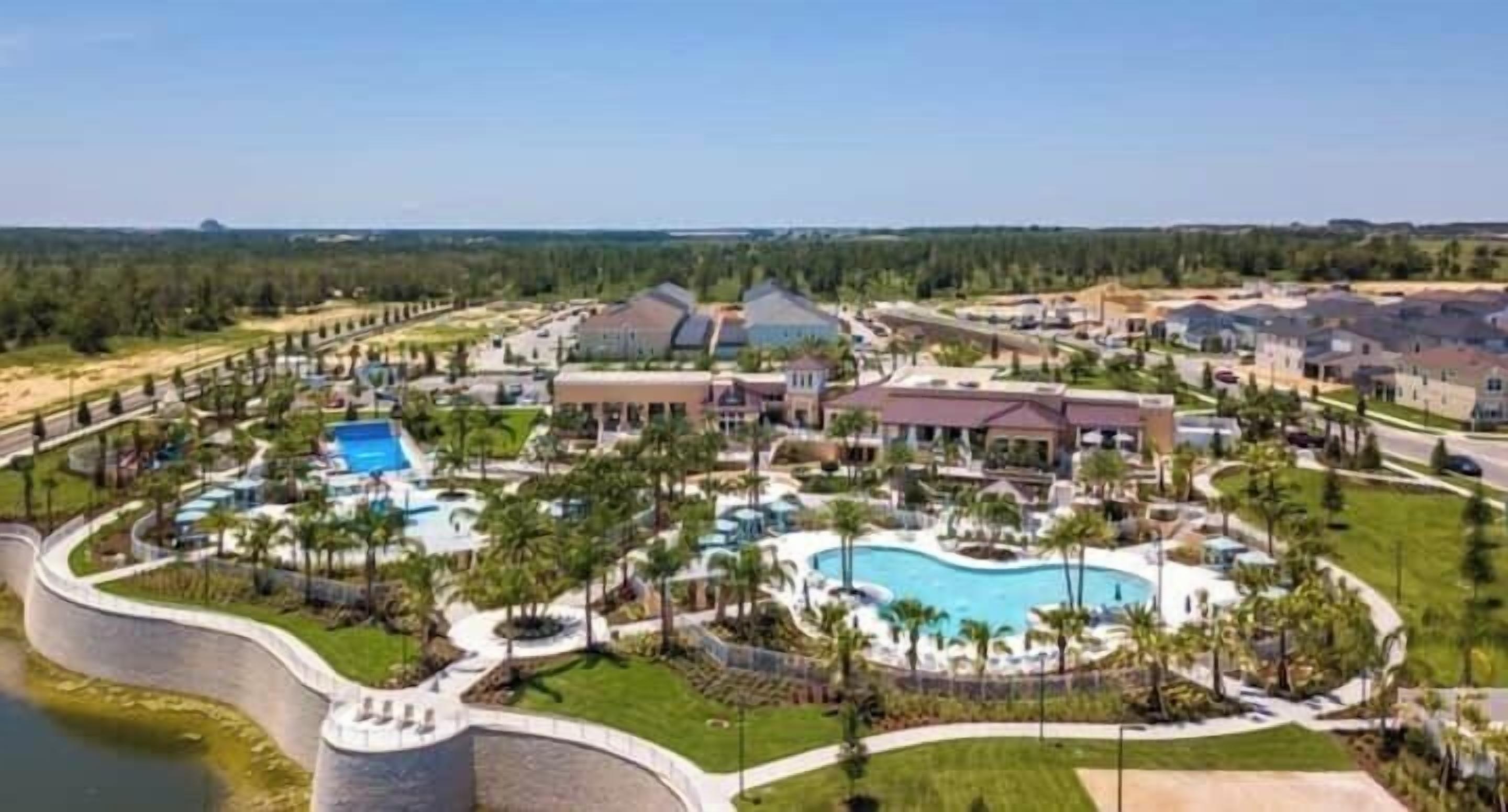 A resort with multiple buildings, a large central pool, and surrounding greenery.