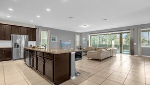 A spacious kitchen with a central island, dark wooden cabinets, and a stainless steel refrigerator. - Luxury 9Beds Villas With Pool Spa In Solara (Four Corners)