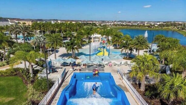 A water park with a large pool, palm trees, and a view of a lake. - Luxury 9Beds Villas With Pool Spa In Solara (Four Corners)