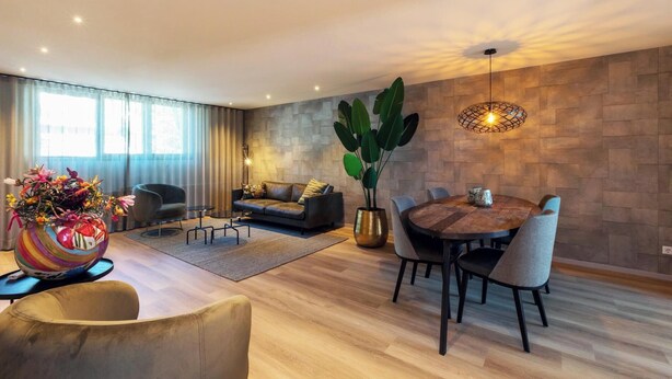 A modern living room with a sofa, coffee table, and dining area.
