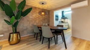 A dining area with a wooden table, four chairs, a large potted plant, and a unique ceiling light fixture.