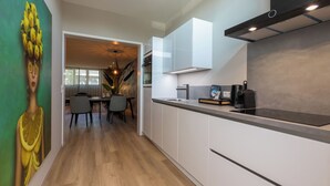 A modern kitchen with white cabinetry, a black countertop, and a visible coffee machine.