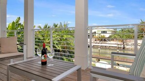 A covered outdoor seating area with a table and chairs, a bottle of wine, and a glass on the table. - Sombrero Beach Retreat w/ 60' Dock & Private Pool! (Marathon)