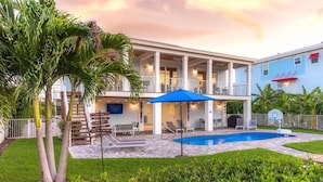 A two-story building with a pool, outdoor seating, and a covered patio area. - Sombrero Beach Retreat w/ 60' Dock & Private Pool! (Marathon)