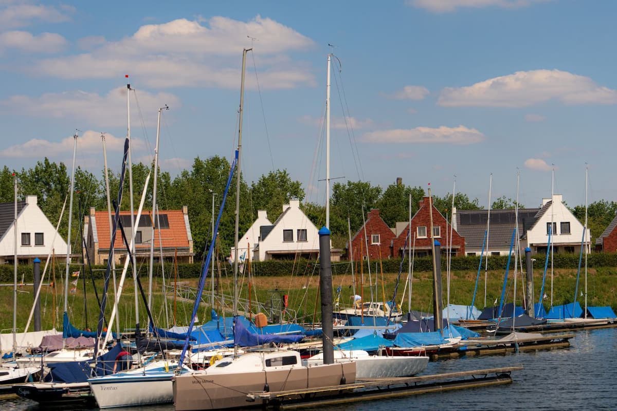 Un port de plaisance où sont amarrés des bateaux, entouré de maisons présentant des styles architecturaux différents.