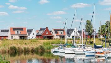 A marina with several sailboats docked, surrounded by residential buildings with red and grey roofs.