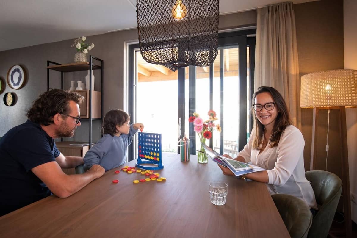 Un coin repas avec une table en bois, un jeu de société et un vase rempli de fleurs.