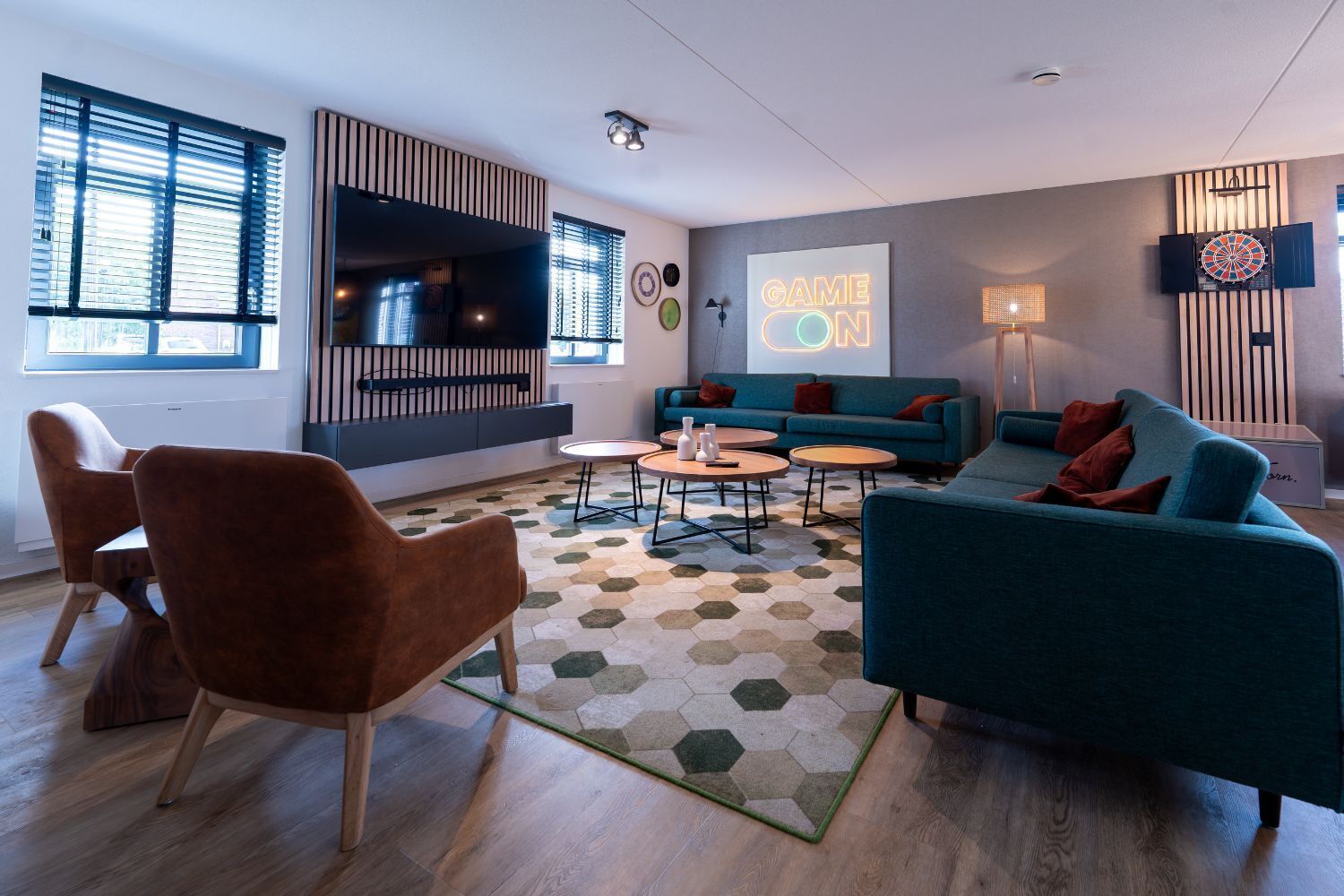 A modern living room with a sofa, chairs, a coffee table, and a dartboard.
