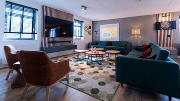 A modern living room with a sofa, chairs, a coffee table, and a dartboard.