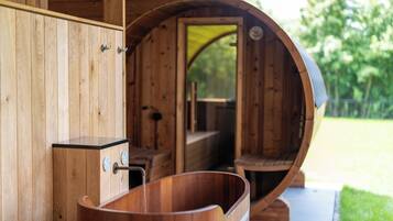 Een houten blokhut met een ronde binnenruimte, een houten badkuip en een houten kastje met een kraan.