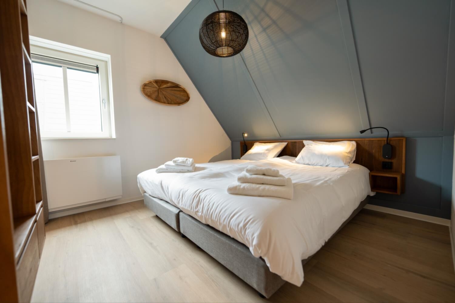 A bedroom with a bed, bedside tables, a window, and a ceiling light fixture.