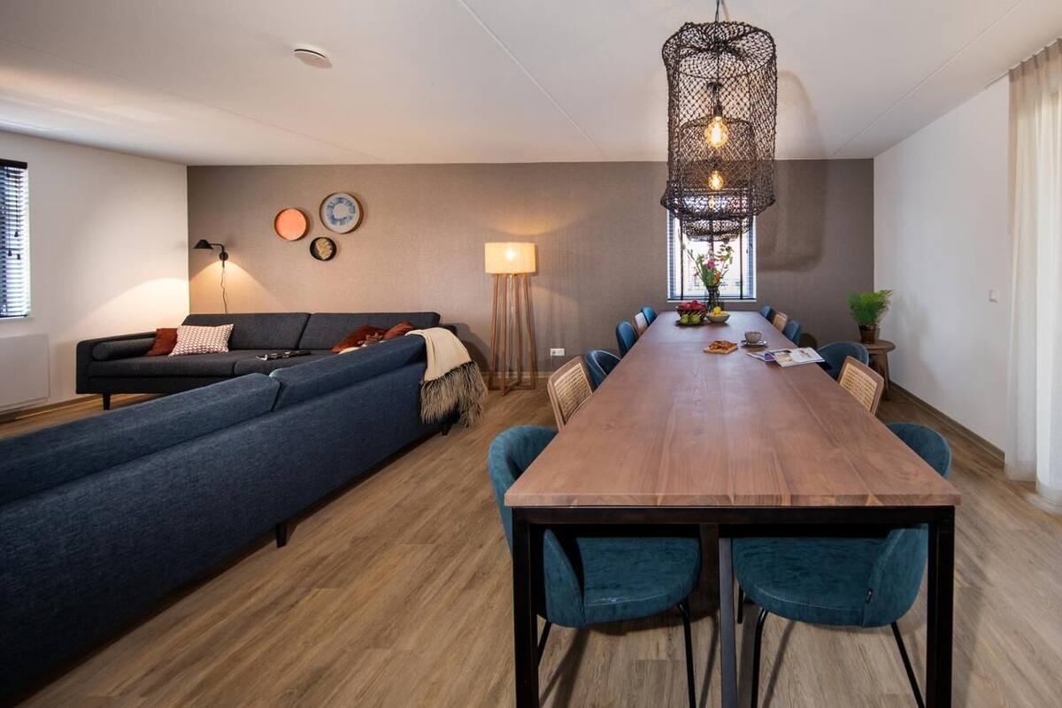 Un salon moderne avec un canapé, une table à manger et des chaises. On y trouve une lampe et un luminaire suspendu.