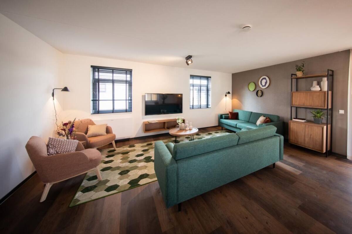 Un salon moderne comprenant un canapé, des fauteuils, une table basse et un téléviseur.
