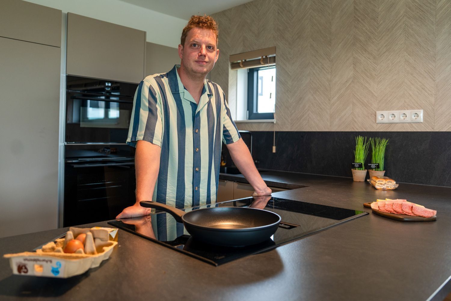Una cocina moderna con estufa integrada, una olla sobre la estufa y un tazón de huevos en la encimera.
