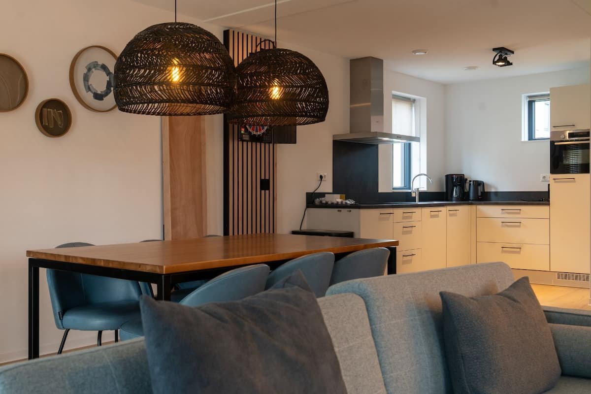 Une cuisine moderne avec un coin repas, comprenant une table en bois, des chaises bleues et un canapé gris.