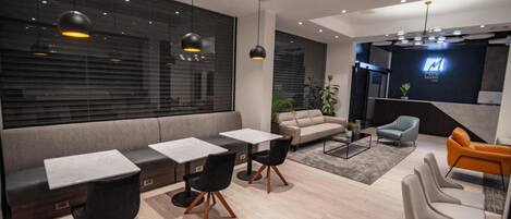 A modern interior with a sofa, two tables with chairs, a coffee table, and a TV mounted on the wall.