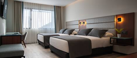 Une chambre d’hôtel moderne, dotée d’un grand lit, d’un bureau et d’une télévision.