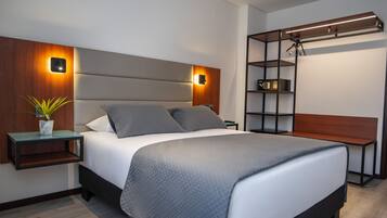 A modern bedroom with a large bed, bedside tables, a nightstand, a wall-mounted shelf, and a hanging light fixture.
