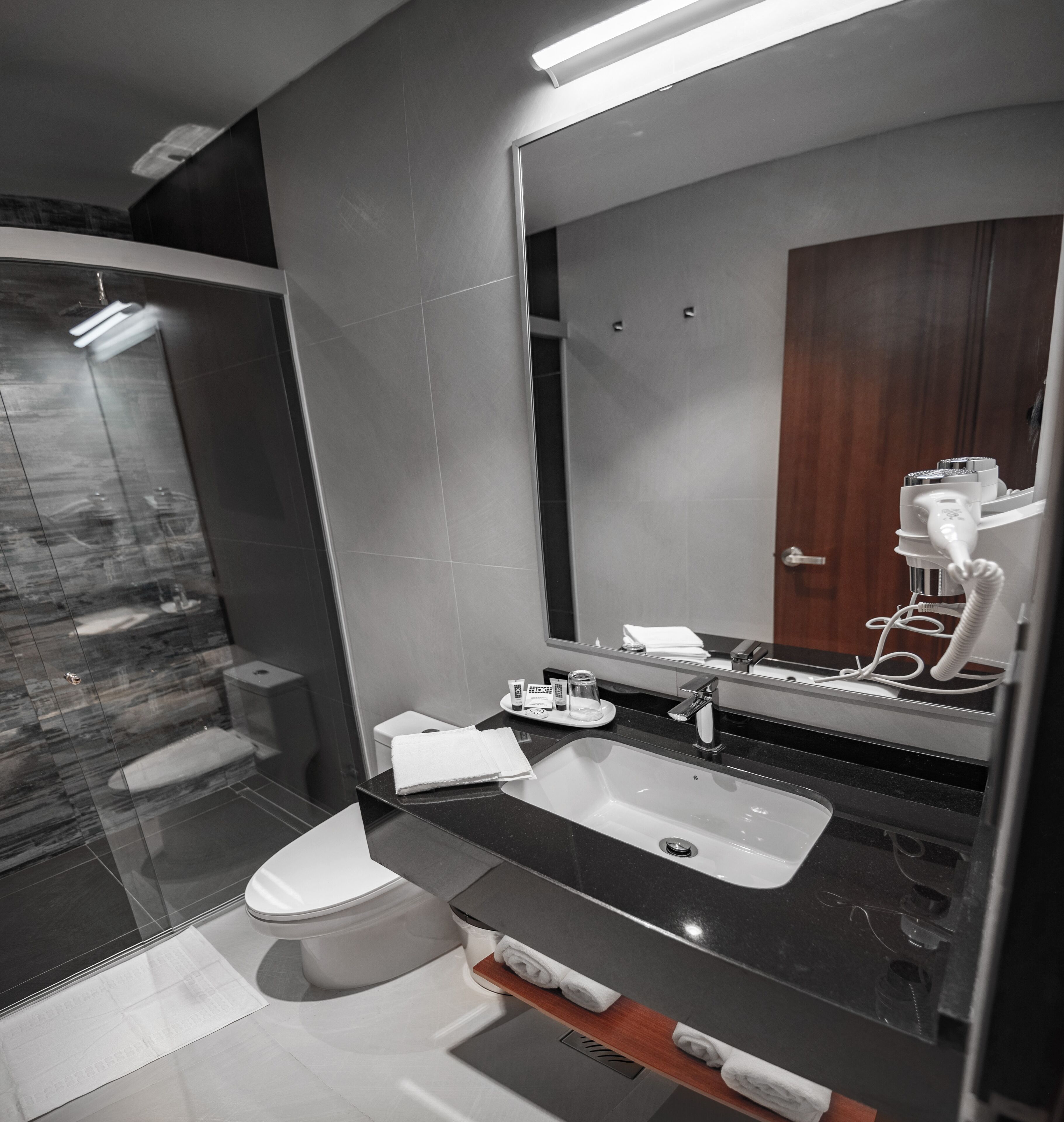 A modern bathroom with a large mirror, a sink, and a toilet.
