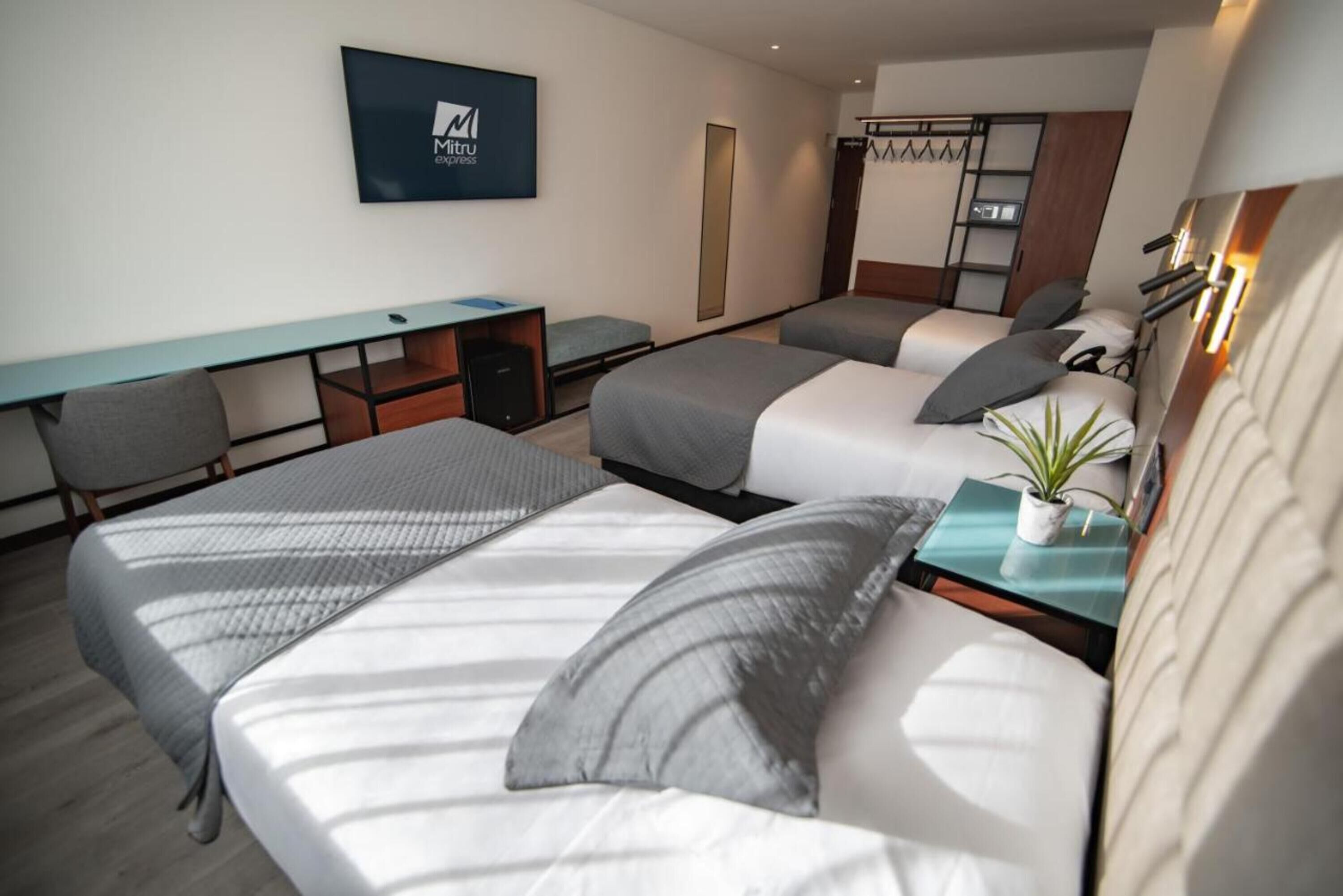A hotel room with two beds, a desk, a TV, and a wardrobe.
