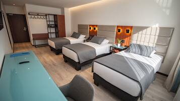 A hotel room with two beds, a desk, and a chair. There is a coat rack and a wardrobe.